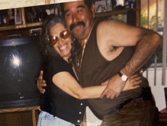 Two friends smile and embrace in a cozy, laughter-filled indoor setting.