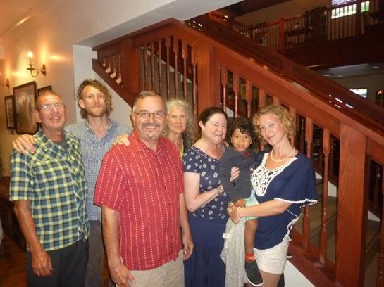Family members pose together on a wooden staircase, showcasing smiles and joy in a warm environment.