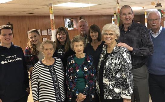A joyful gathering of seniors smiling and enjoying each other's company in a warm setting.