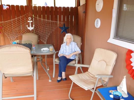 A woman relaxes on a comfortable chair in a coastal home, surrounded by nautical decor.