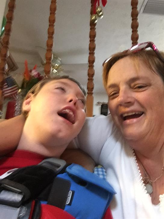 A caregiver is smiling and laughing with a child, sharing a heartwarming moment in a home.
