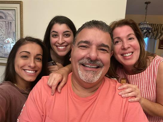 Four family members share a joyful moment together, smiling and enjoying each other's company.