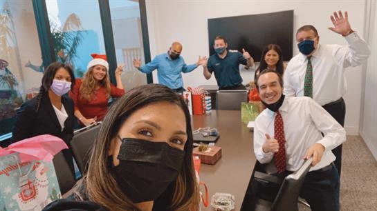 Team members celebrate the holiday season together while wearing face masks in the office.