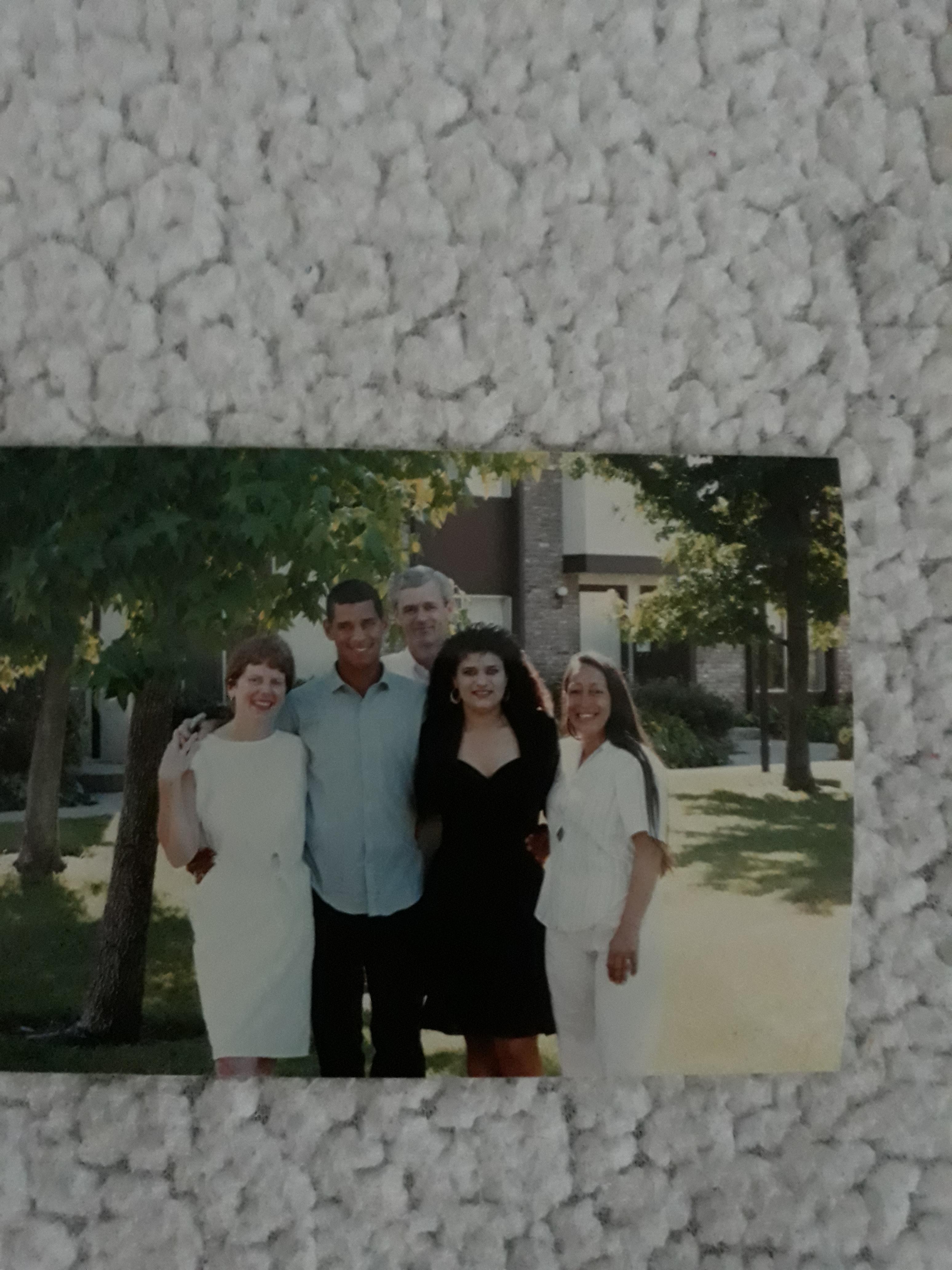 Group of five friends enjoying a sunny day outdoors, smiling and posing in a backyard setting.