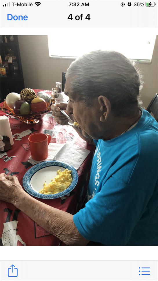 Elderly man savors a plate of scrambled eggs at the kitchen table, enjoying his meal.