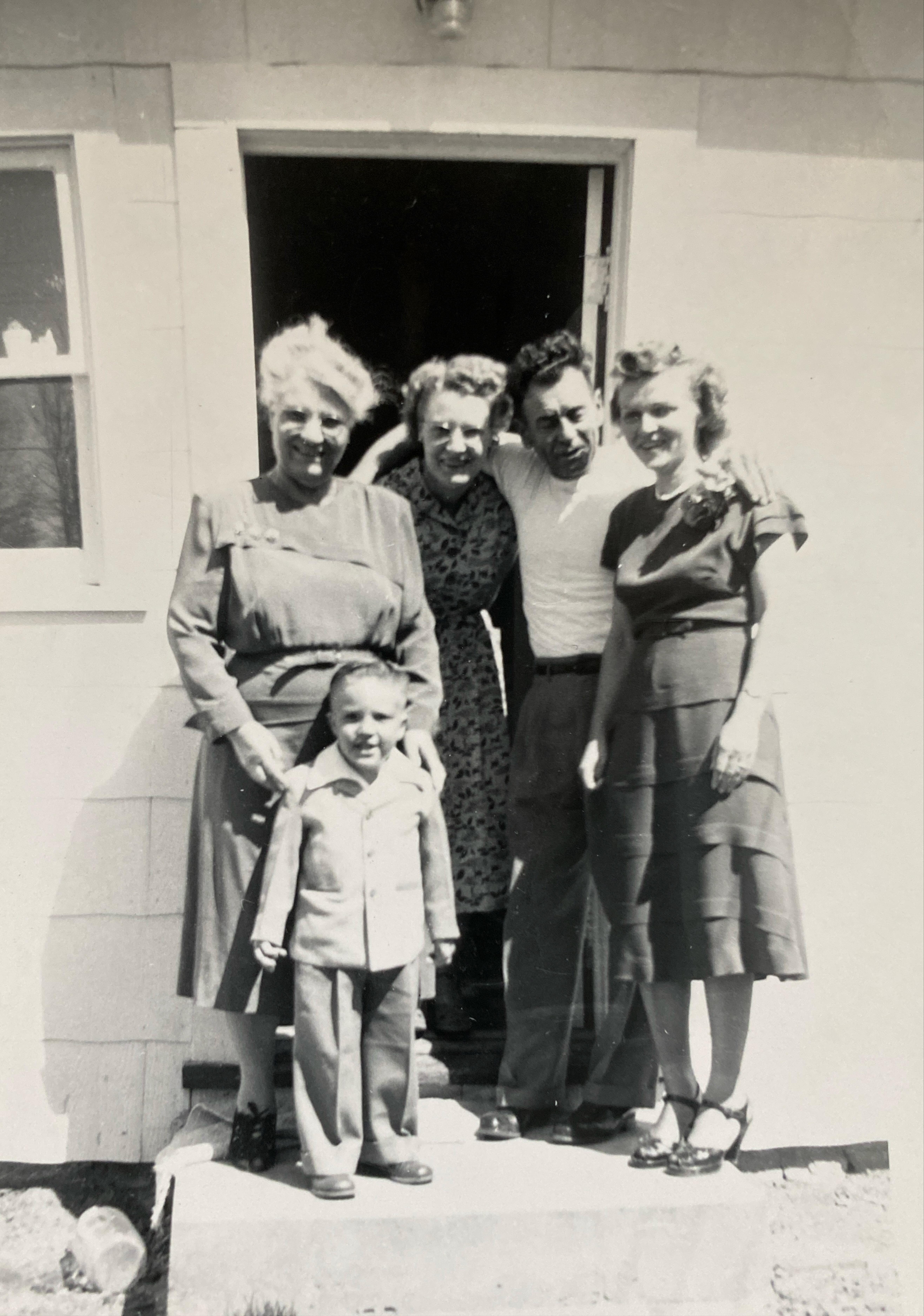A family stands together at the entrance of their home, smiling and sharing a moment.