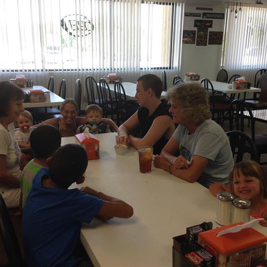 Group of adults and children share laughter and conversation at a family-friendly restaurant.