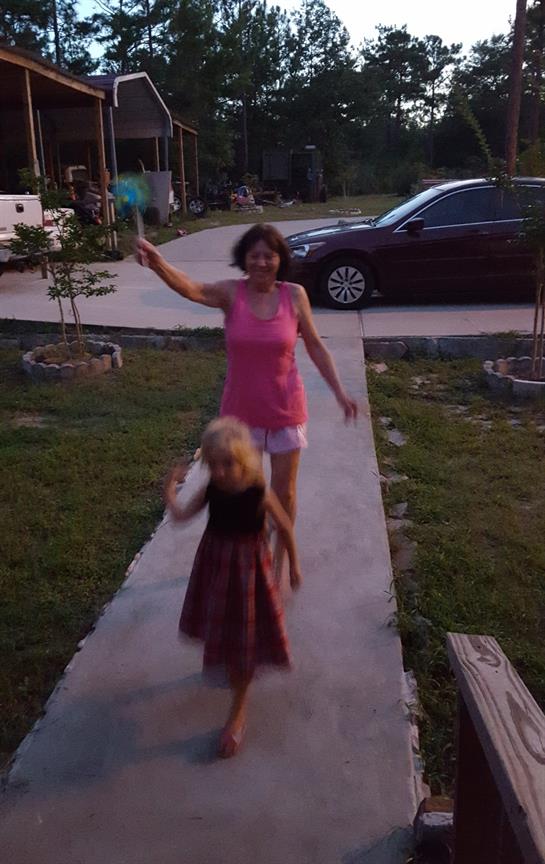 A woman and a young girl are happily walking along a pathway during early evening hours.
