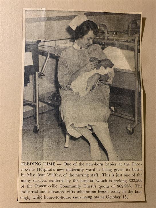 Caregiver gently holds and feeds a newborn baby in a hospital nursery, showcasing maternal care.