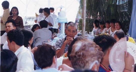 Guests enjoy food and drinks at a bustling outdoor restaurant during a lively gathering.