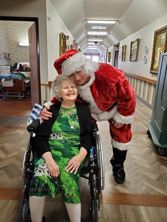 Santa cheerfully interacts with a resident in a nursing home during the holiday festivities.