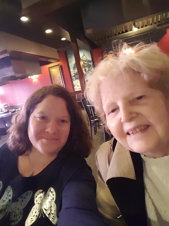 Two friends smile while sitting at a table in a charming restaurant during lunch.