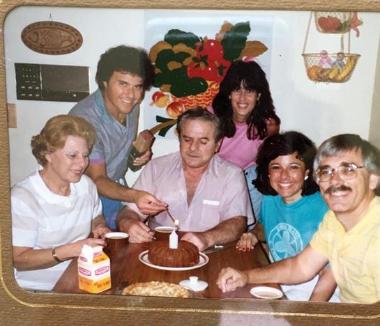 Loved ones gather around a table to celebrate, sharing laughter and cake in a warm kitchen.