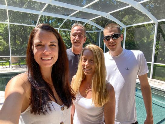 Four friends gather by the sparkling pool, smiling and enjoying a sunny afternoon outdoors.