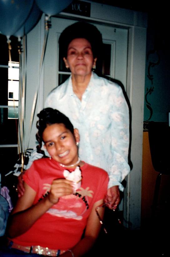 A young girl holds an ice cream cone while smiling at her grandmother in a cozy indoor setting.
