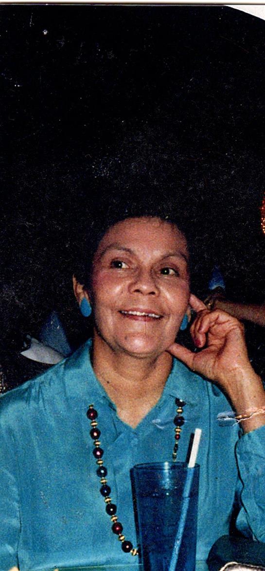 A smiling woman enjoys a lively conversation with friends at a gathering during the evening.