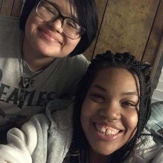 Two friends pose for a cheerful selfie in a warm, inviting atmosphere at home.