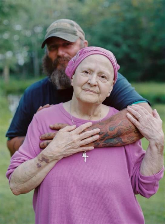A woman in a pink top and headscarf smiles while being embraced by a man, showcasing love.