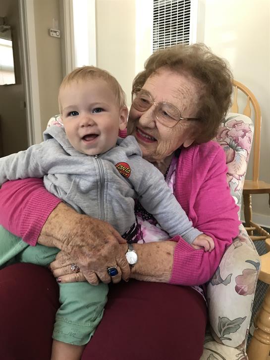 A grandmother shares a warm moment with her smiling grandchild in a comfortable chair.