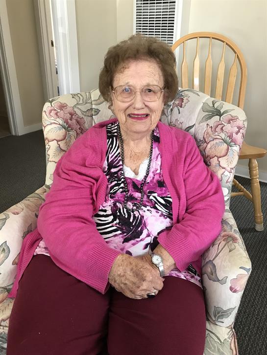 A warm atmosphere surrounds an elderly woman in vibrant colors, smiling and enjoying herself.