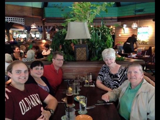Five friends enjoy drinks and laughter at a lively restaurant table.