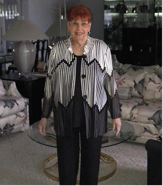 A stylish woman stands in a contemporary living room filled with elegant furniture and decor.