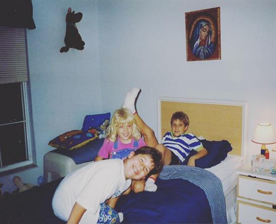 Three kids engage in playful activities in a cozy bedroom setting.