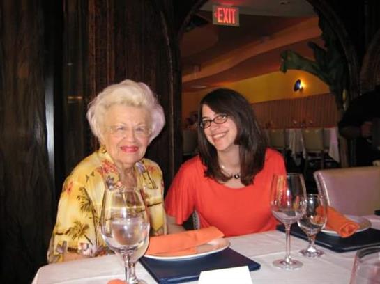 Two women share a joyful moment at a restaurant, surrounded by elegant decor and dinnerware.