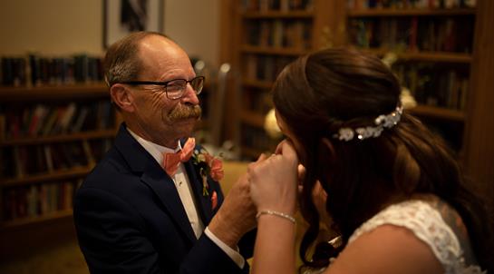 A father and daughter share a touching moment while dancing at an intimate wedding reception.