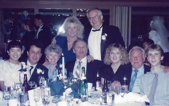 Guests gather around a beautifully set table, celebrating a special occasion in formal wear.