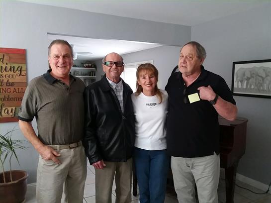 Four friends enjoy each other's company, smiling and chatting in a bright, cozy living room.