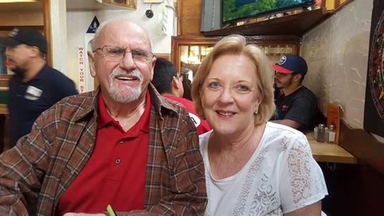 A couple happily poses together at a restaurant, enjoying their evening with friends.