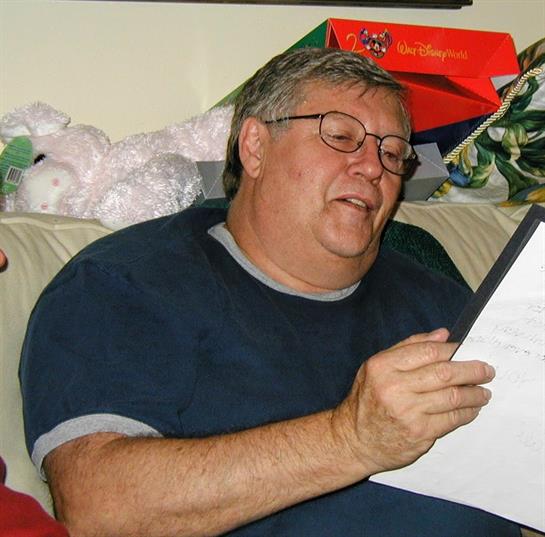 Man enjoys a moment reading an invitation on a cozy couch filled with decorations.