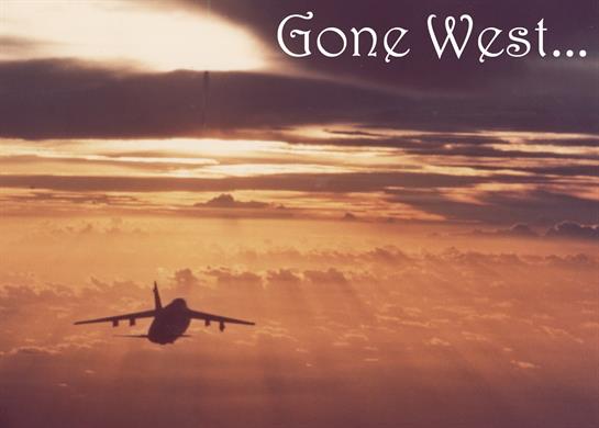 A plane heads toward a sunset, bathing the clouds in warm hues and a serene atmosphere.