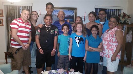 A large family gathers for a reunion in a cozy living room, smiling and sharing joyful moments.