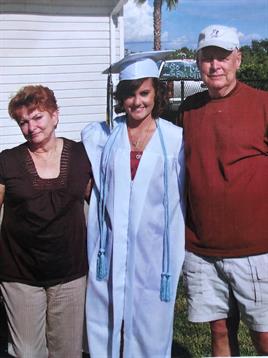Family gathers for a joyful graduation celebration in a sunny outdoor location.