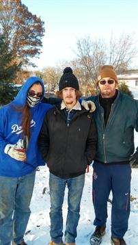 Friends pose in the snow, showing off their winter outfits and smiling on a chilly day.