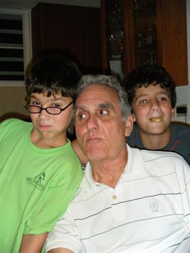 Two young boys pose with their grandfather at home, enjoying a relaxed evening together.