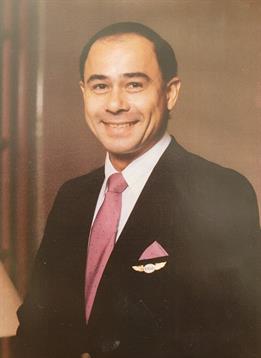 A man in a tailored suit smiles confidently, showcasing a professional appearance indoors.