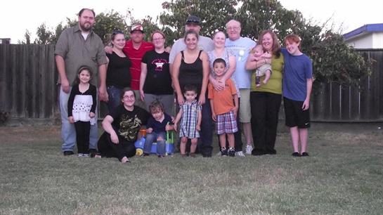 Family and friends gathered in a park for a joyful summer afternoon, enjoying each other's company.