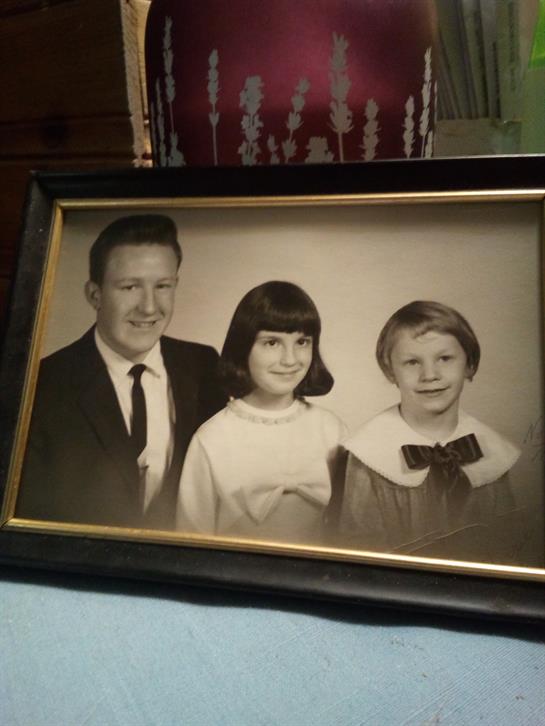 A father poses proudly with his two children, showcasing their joy in a vintage family portrait.