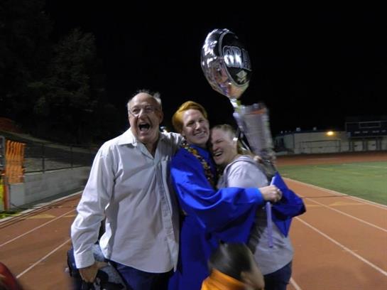 Family celebrates a graduation under the night sky with joy and excitement.