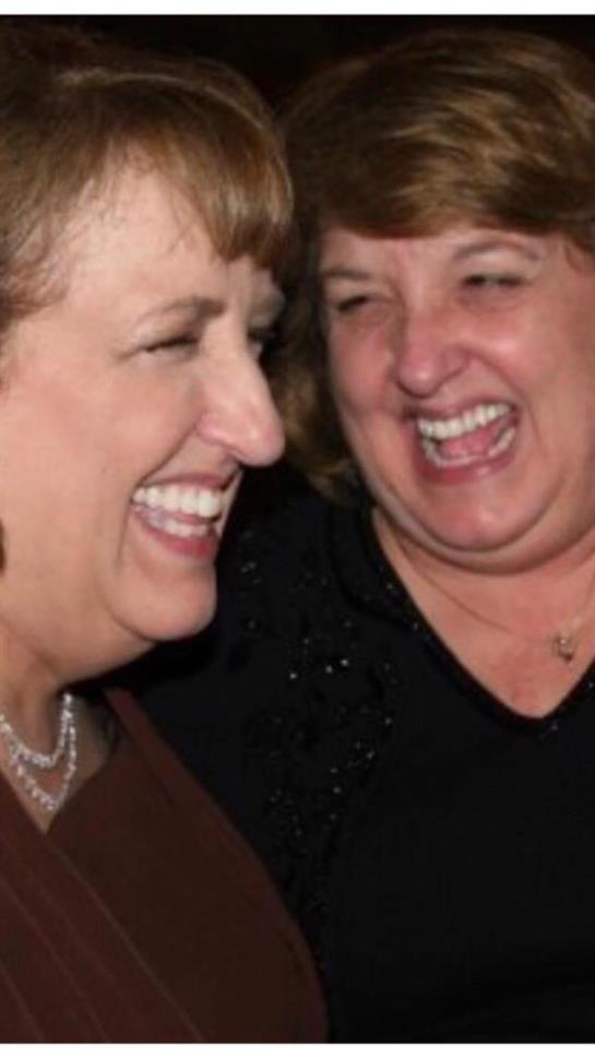 Two friends share a heartfelt laugh, enjoying a fun moment together at a casual gathering.