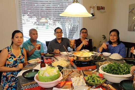 Family members celebrate together over a hot pot meal, sharing laughter and good food.