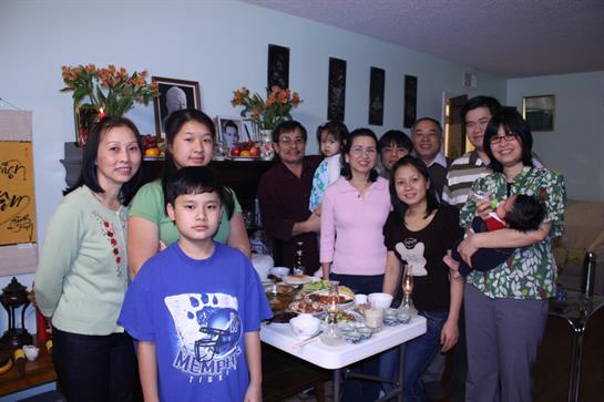 Family members gather in a decorated living room, enjoying a festive meal together.