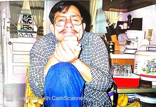 Man smiles happily in a cozy kitchen, showing a relaxed and cheerful demeanor.