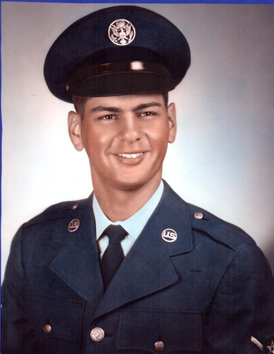 A young man in a military uniform smiles proudly while wearing a cap.