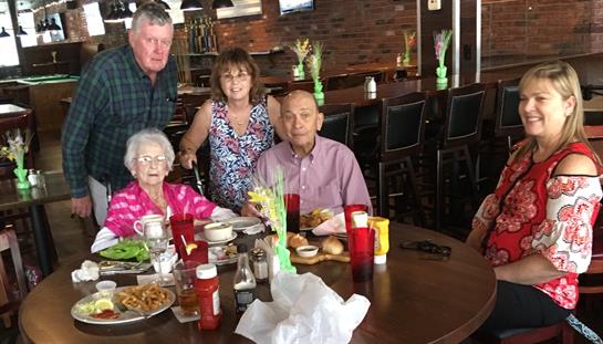 A group of four sits at a table filled with food, sharing a joyful moment at a restaurant.