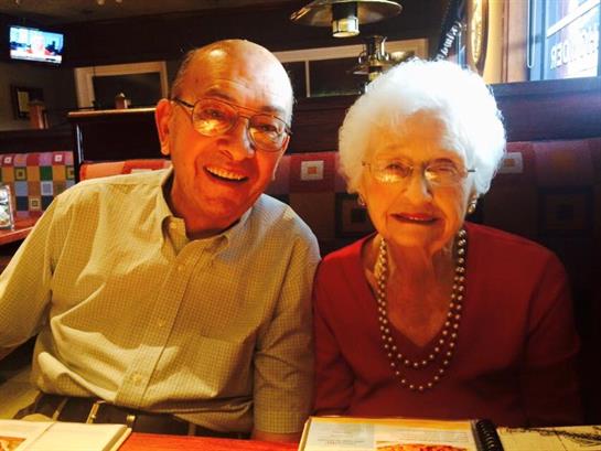 Smiling couple sitting at a restaurant table, enjoying each other's company and a meal.