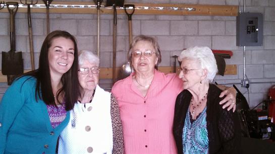 Four women from different generations stand close together, smiling and enjoying a family moment.